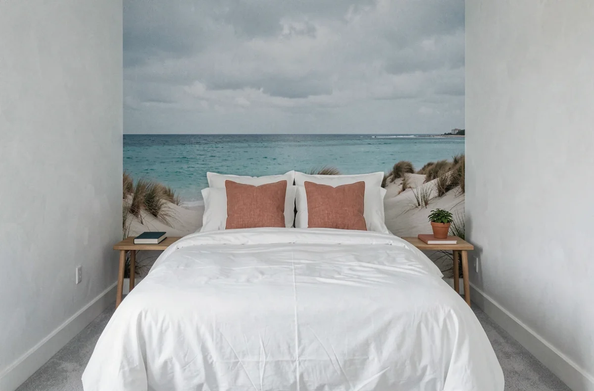 Chambre moderne avec papier peint panoramique bord de mer dunes et mer turquoise derrière un lit en coton blanc